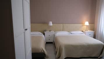 A hotel room with two beds, a nightstand with lamps, and a door.