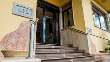 Entrada de hotel con una escalera de mármol, una barandilla metálica y un letrero que indica el nombre del hotel.