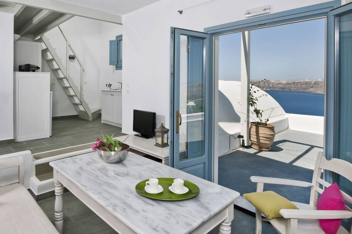 Un salon moderne avec une table en marbre, un canapé et un balcon offrant une vue sur la mer.