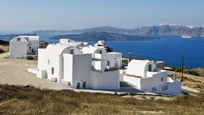 A coastal village with white buildings, a clear blue sea, and distant mountains. - Aura Marina Apartments Santorini (Santorini)