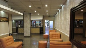 A lobby with a bar area, seating, and a view of the outdoors. - Le Dune (Castel Volturno)