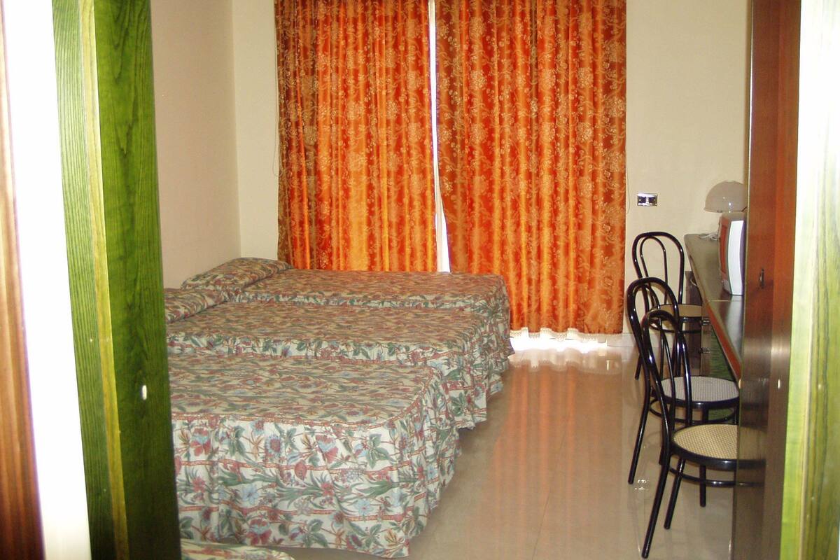 A room with two beds, a desk, and two chairs.