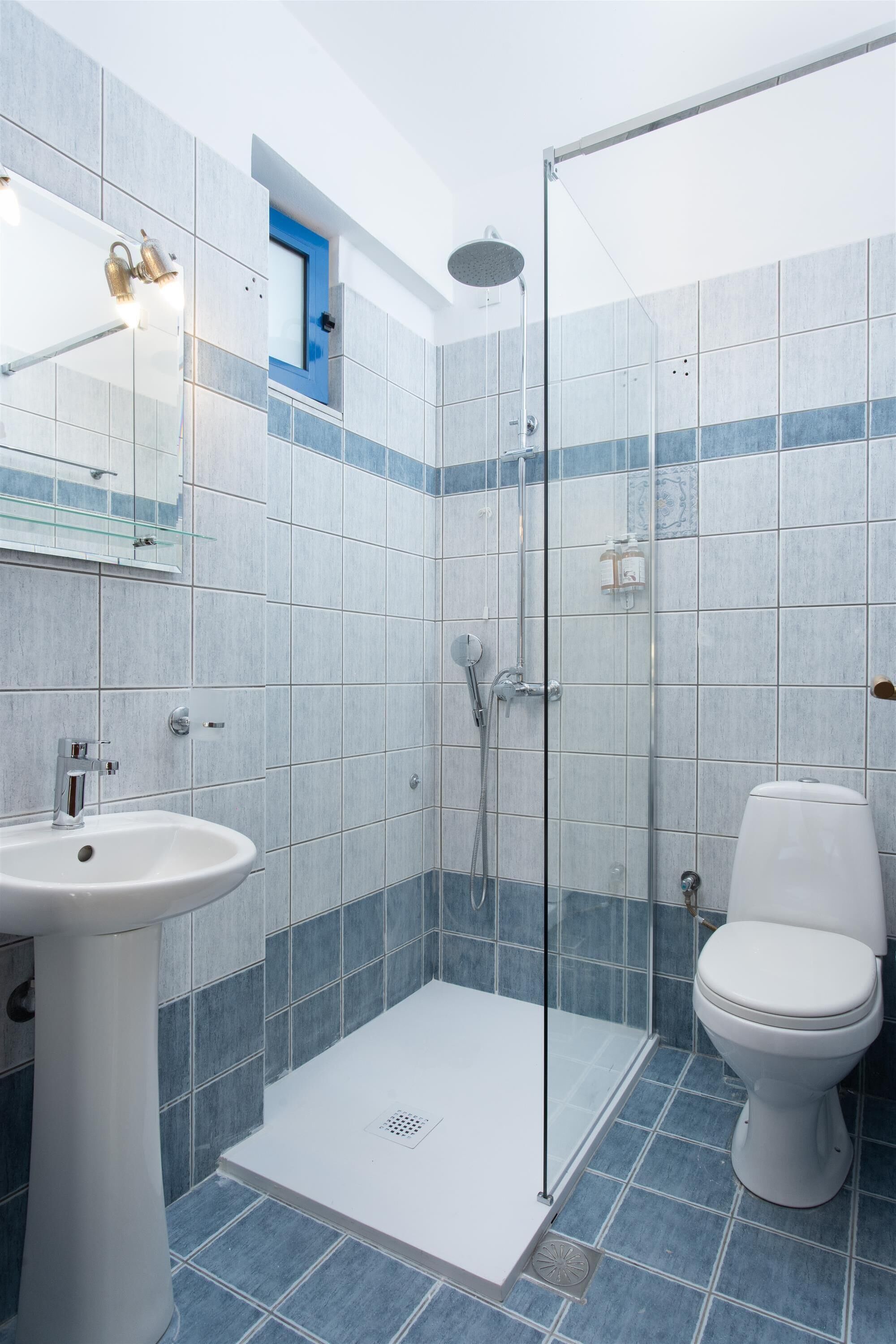 A bathroom with a glass-enclosed shower, a white sink, and a toilet.