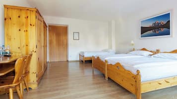 Une pièce comprenant un lit en bois, une armoire en bois, un bureau avec des chaises et un tableau encadré accroché au mur.