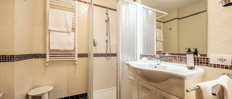 A modern bathroom with a glass shower enclosure, a white sink, and a toilet.