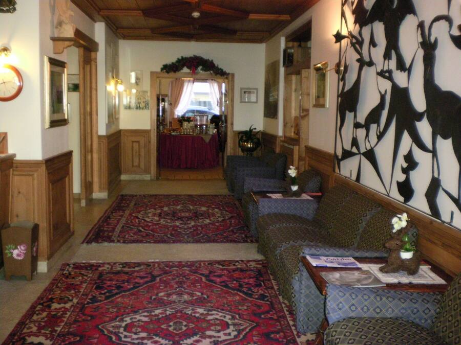 Un intérieur traditionnel avec un tapis à motifs, un banc en bois et un mur orné d’un motif abstrait en noir et blanc.