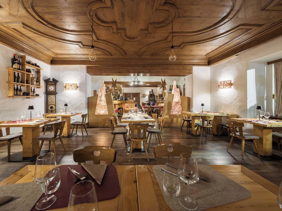 A restaurant with wooden furniture, a central bar area, and a rustic ceiling design.