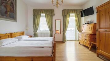 Una habitación de hotel con una cama de madera, un televisor, un aparador de madera y una araña.