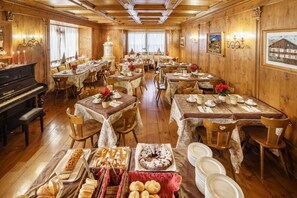 Un comedor con varias mesas dispuestas para comidas, un piano y obras de arte enmarcadas en las paredes.