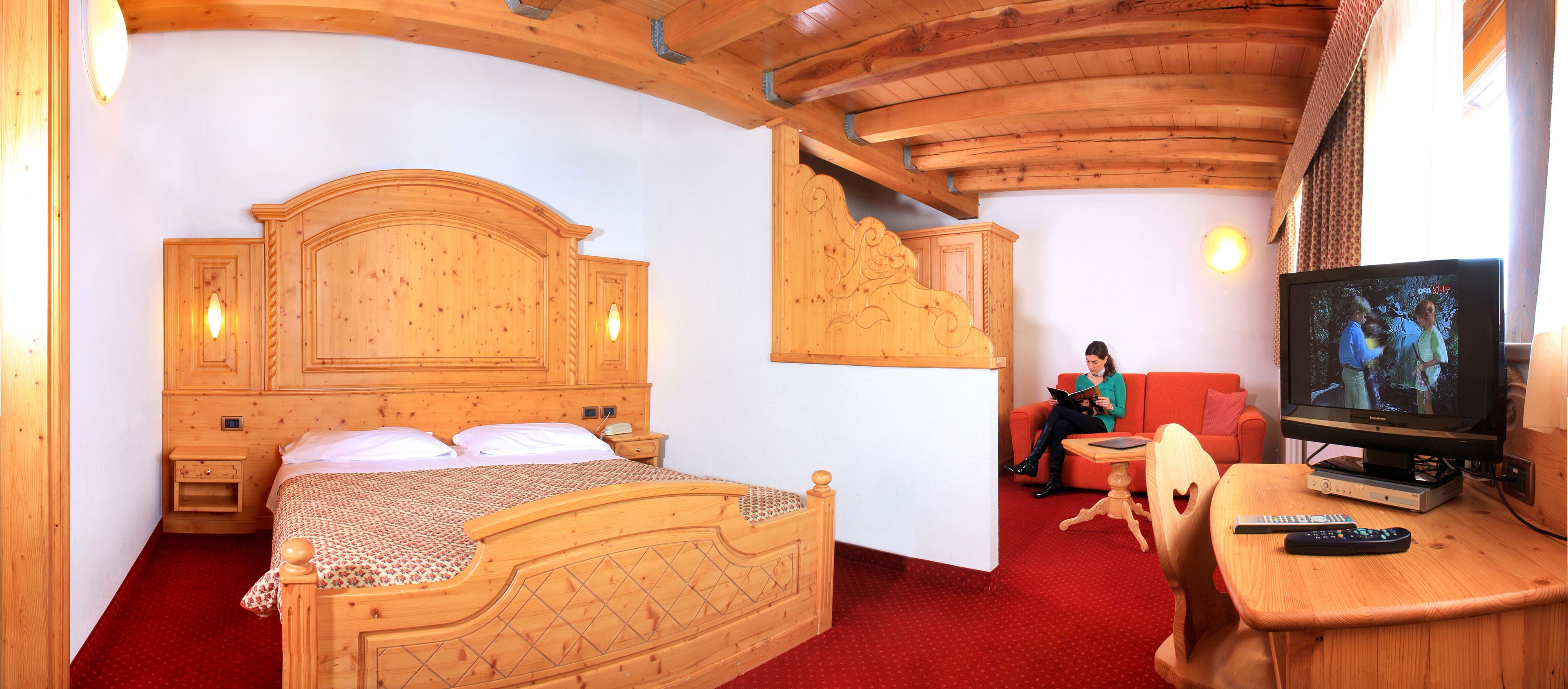 Una habitación de madera con una cama, un televisor y una alfombra roja.