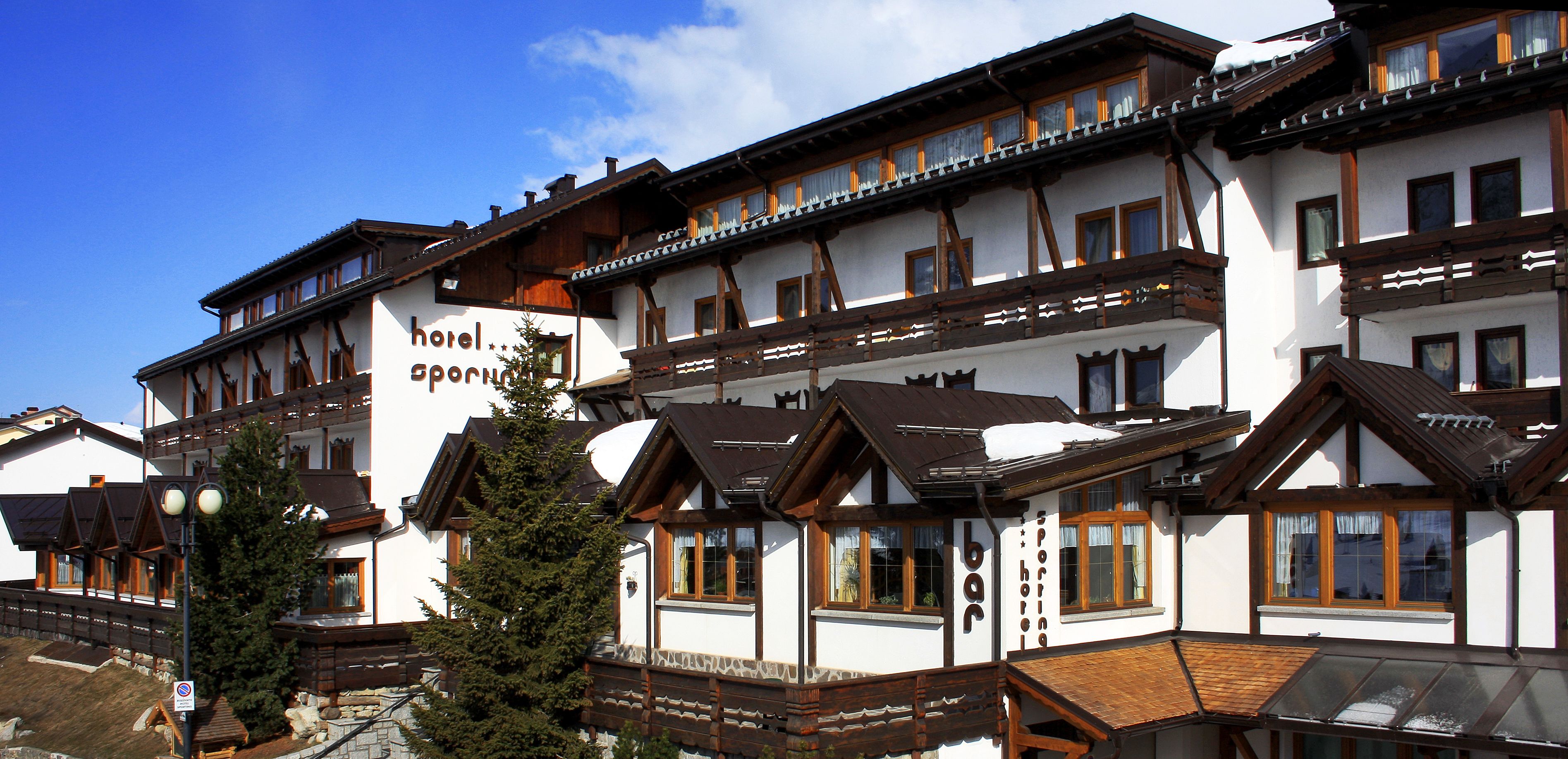 A multi-story hotel with traditional Alpine architecture, featuring wooden balconies and large windows.