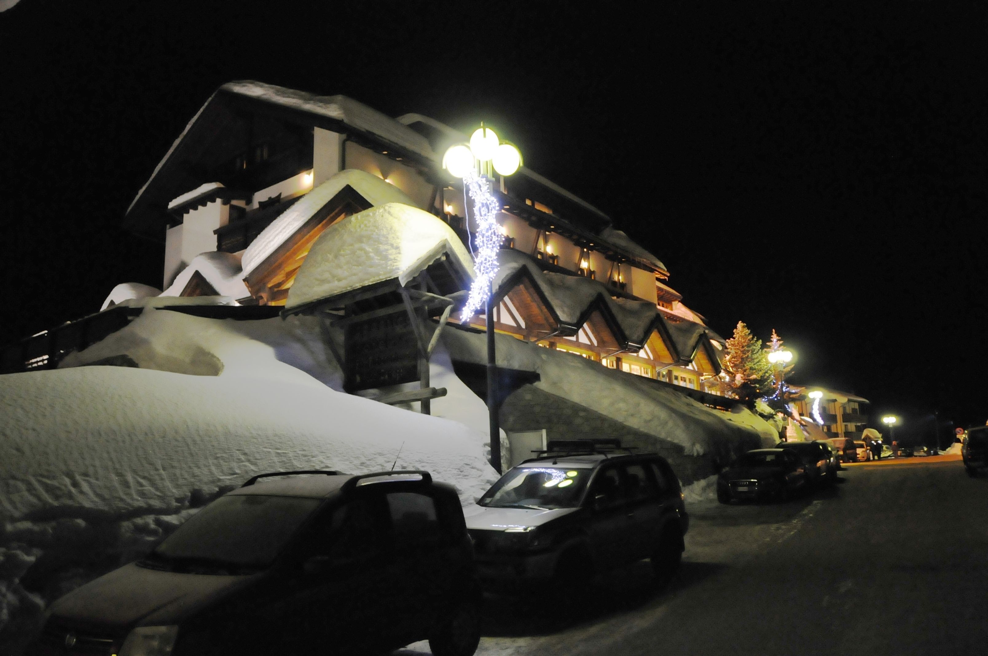 A snow-covered building with a sloped roof and a lit signboard.