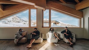 Una habitación con ventanas amplias, vigas de madera y vistas a un paisaje nevado.