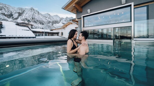 Una pareja en una piscina con montañas al fondo.