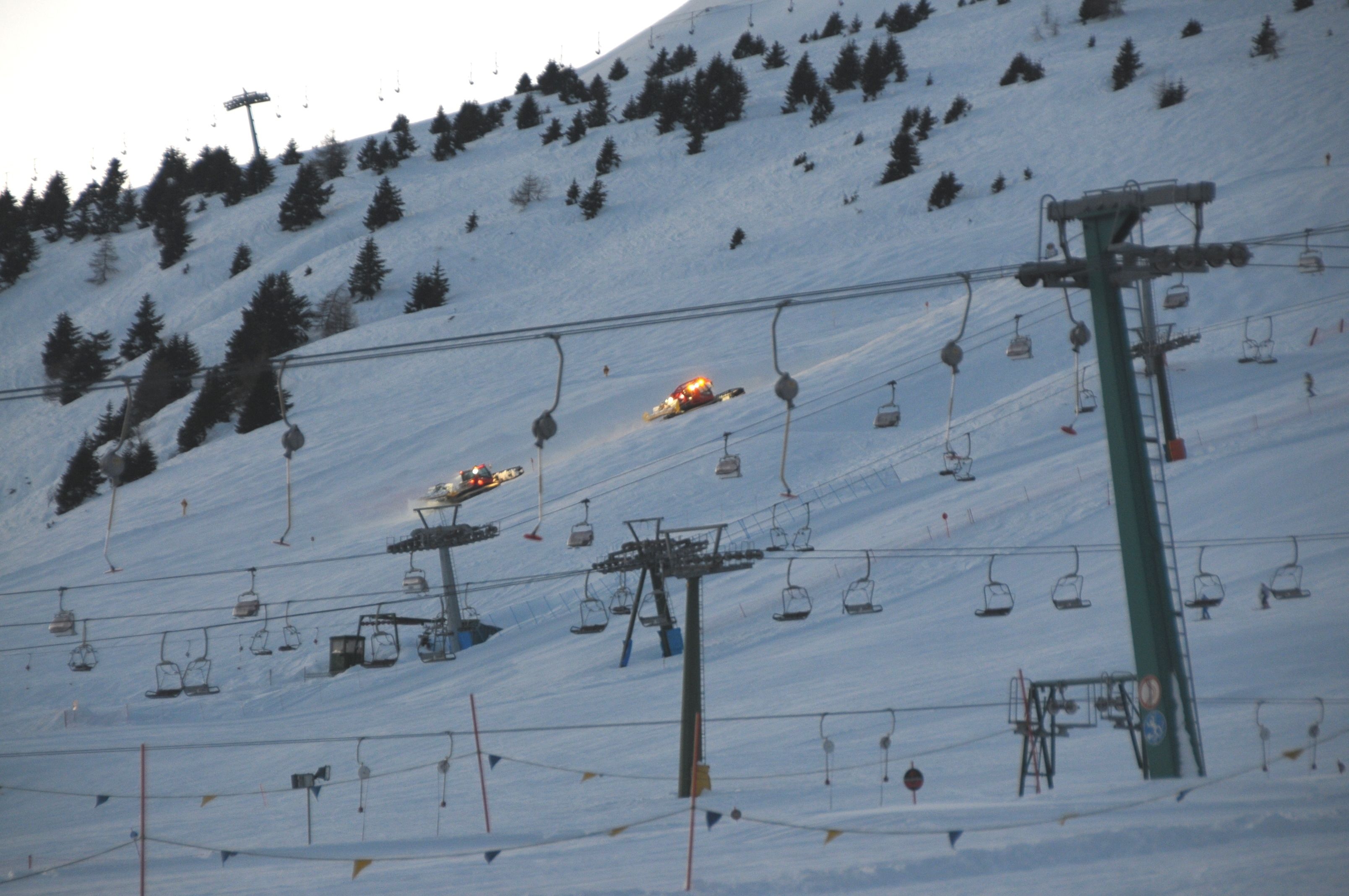 A ski lift with chairs moving up and down a snowy slope.
