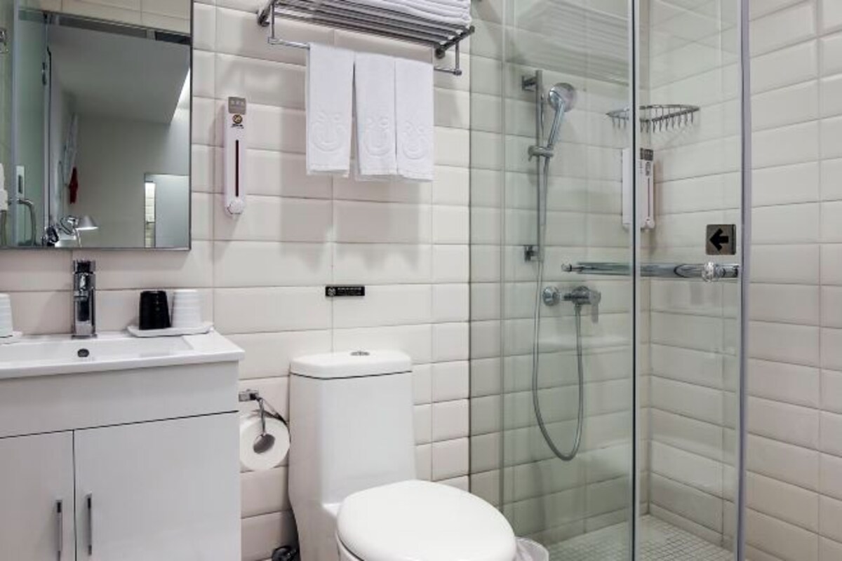 A modern bathroom with a toilet, sink, and glass-enclosed shower.