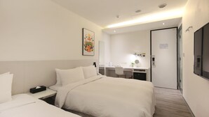 A hotel room with a bed, bedside table, desk, chair, and a mirror.