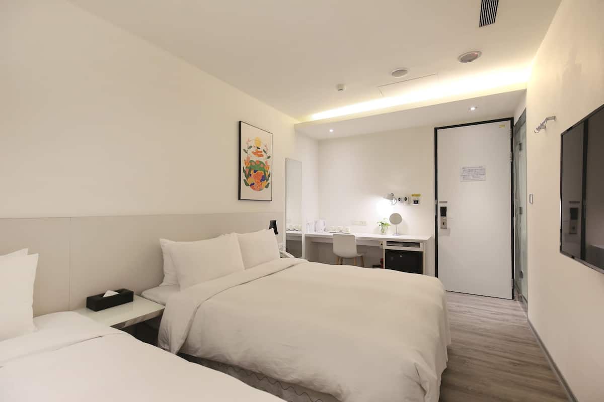 A hotel room with a bed, bedside table, desk, chair, and a mirror.