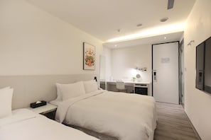 Quarto de hotel com cama, mesa de cabeceira, escrivaninha, cadeira e espelho.