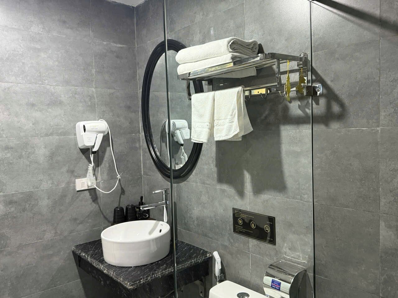 Une salle de bain moderne avec un lavabo rond, un porte-serviettes, un miroir et des toilettes.