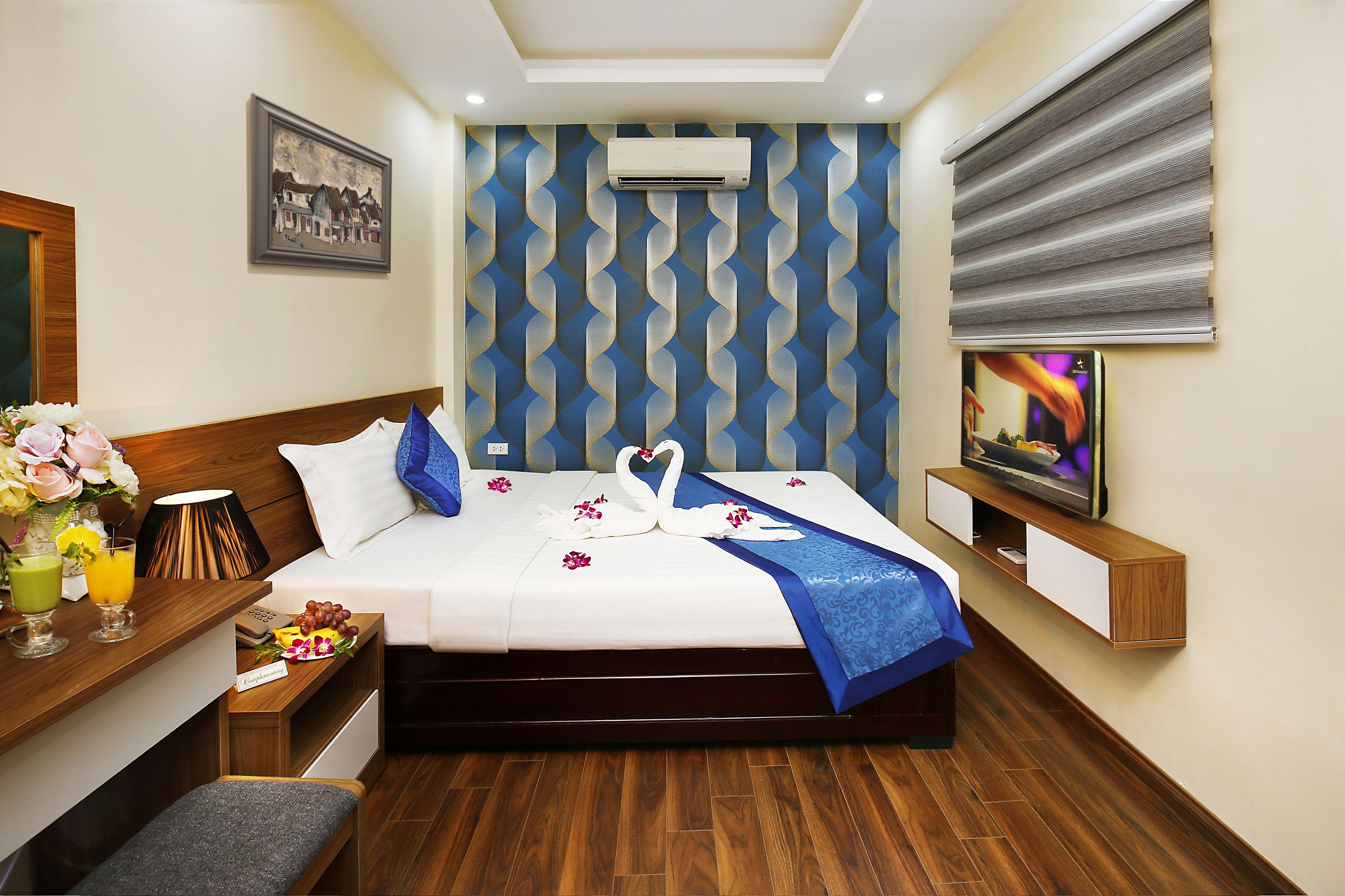 Una habitación de hotel con cama, televisión, escritorio y aire acondicionado instalado en la pared.