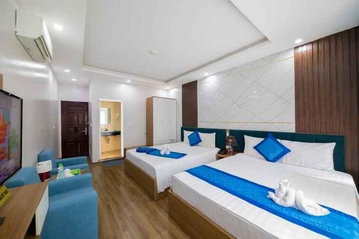 Une chambre d’hôtel avec deux lits, un bureau et une télévision.
