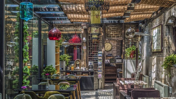 Un café interior con mesas y sillas, una pared de ladrillo y decoraciones colgantes.