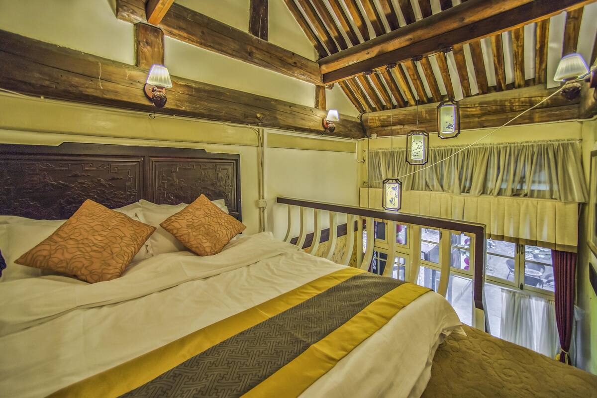 A bed with patterned pillows, a wooden headboard, and a yellow and gray bedspread.