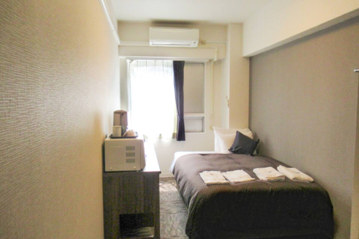 Une chambre d’hôtel équipée d’un lit, d’un bureau avec une lampe et d’un appareil de climatisation.