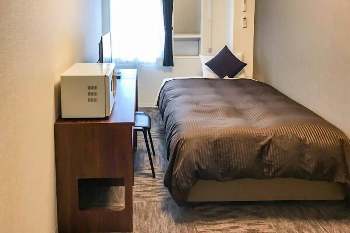 Une chambre d’hôtel avec un lit, un bureau, une chaise et une valise.
