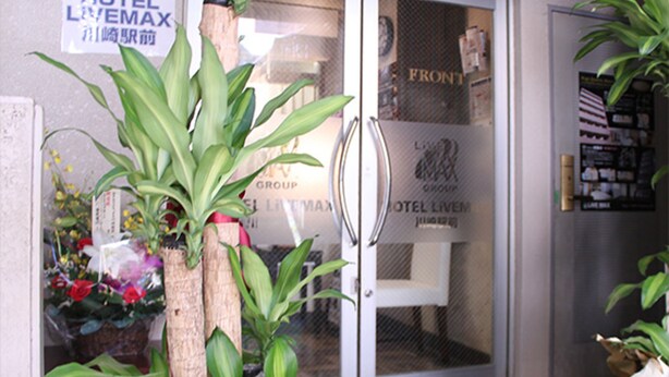 A hotel entrance with a glass door, a doormat, and potted plants. - HOTEL LiVEMAX Kawasaki Ekimae (Kawasaki)