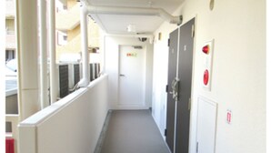 A narrow corridor with a fire extinguisher mounted on the wall, a door at the end, and windows along the left side. - HOTEL LiVEMAX Kawasaki Ekimae (Kawasaki)
