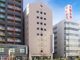 Un edificio hotelero moderno con varios pisos, fachada plana y un letrero llamativo en el centro.