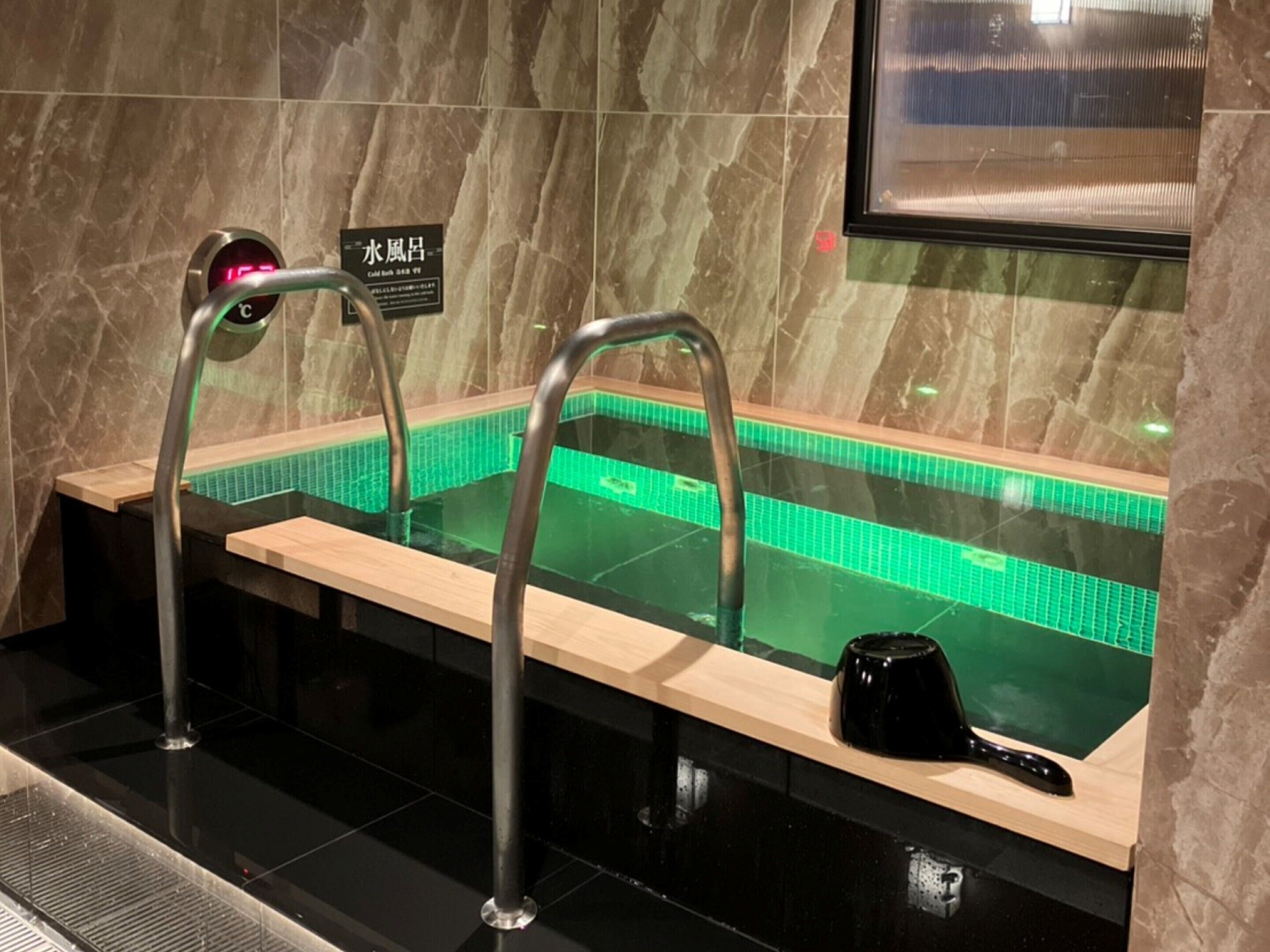 A spa area with a hot tub, metal railings, and a tiled wall.