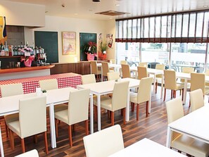 A restaurant interior with multiple tables and chairs, a bar area with bottles, and artwork on the walls. - HOTEL LiVEMAX Hiratsuka Ekimae (Hiratsuka)