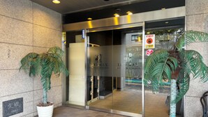 A hotel entrance with a glass door, potted plants, and a sign indicating a no-smoking area. - HOTEL LiVEMAX Hiratsuka Ekimae (Hiratsuka)