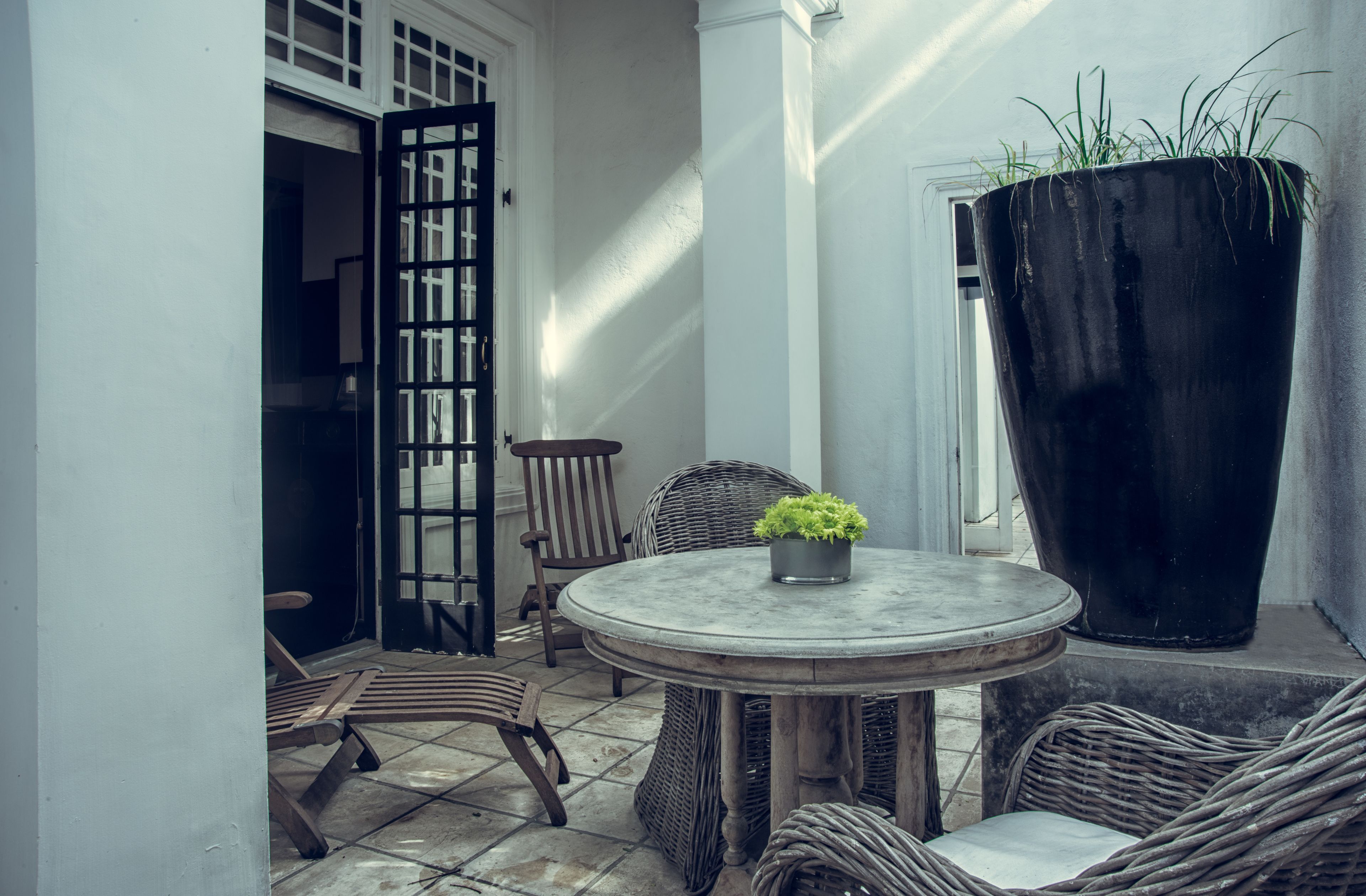 A small, round table with a potted plant, wicker chairs, and a door with a grid pattern.