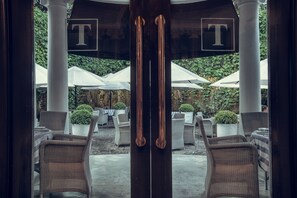 An outdoor seating area with wicker chairs and tables, surrounded by white umbrellas and potted plants. - Paradise Road Tintagel Colombo (Colombo)