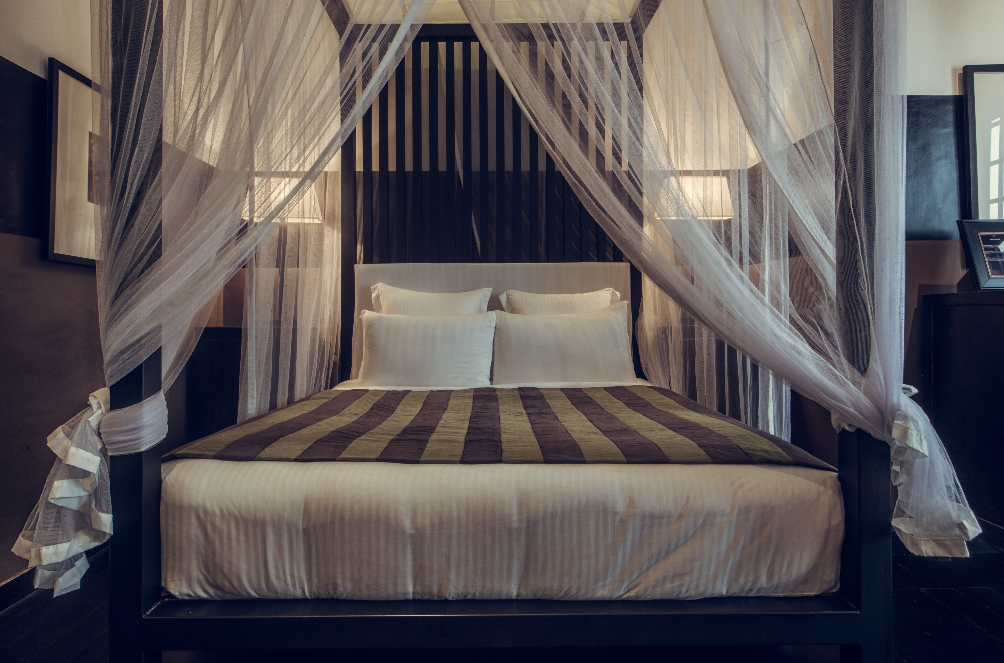 A bed with a striped bedspread, white pillows, and a canopy.