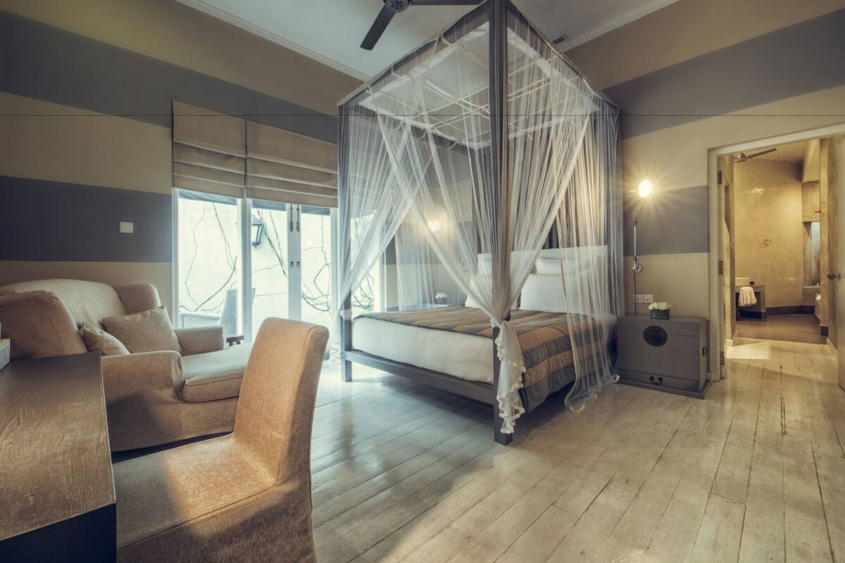 Une chambre à coucher avec un lit à baldaquin, un canapé et une table de chevet.