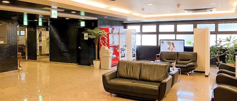 Un lobby moderno con piso pulido, asientos de cuero y una máquina expendedora de Coca-Cola.