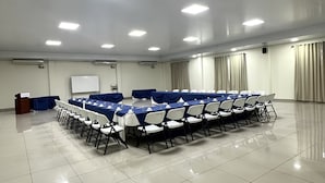 A conference room with a long table, chairs, a podium, and a whiteboard.