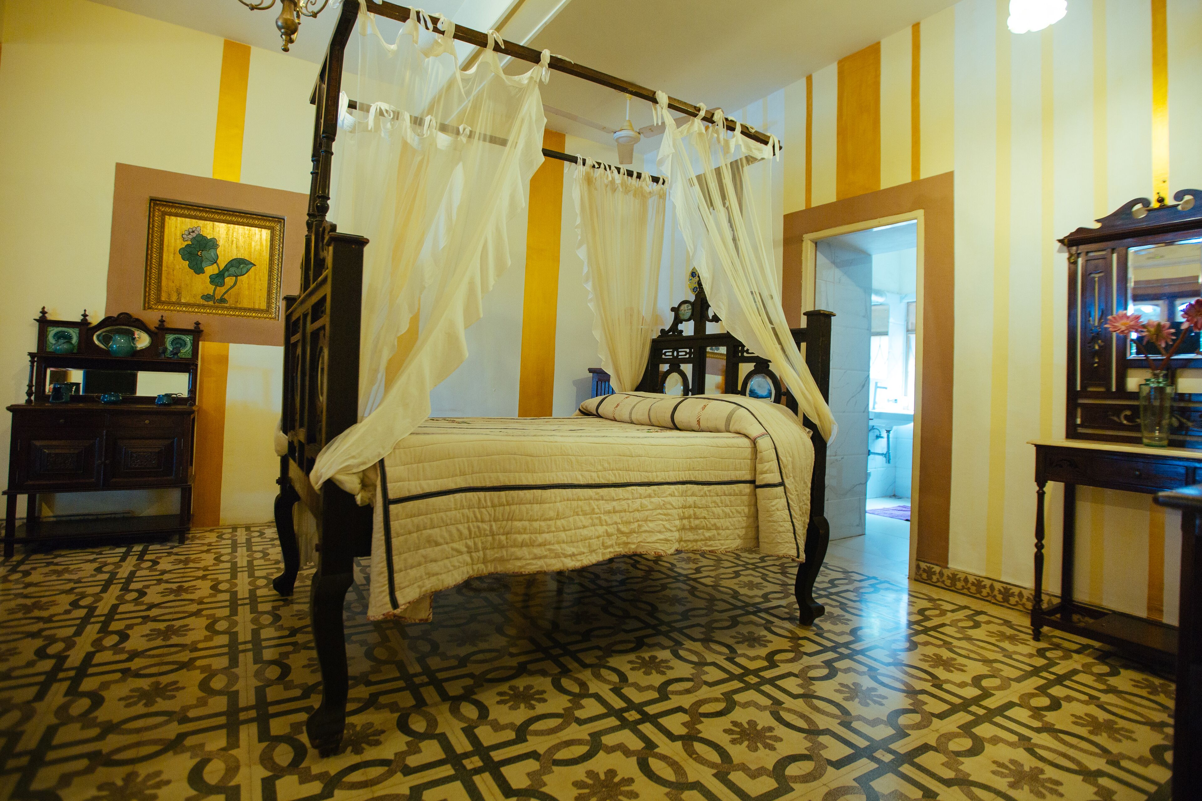 Une chambre à coucher avec un lit à baldaquin, un sol à motifs, un miroir et un tableau accroché au mur.