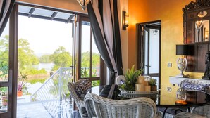 A balcony with wicker furniture, a glass table, and potted plants. - Casa Britona (Alto de Porvorim)