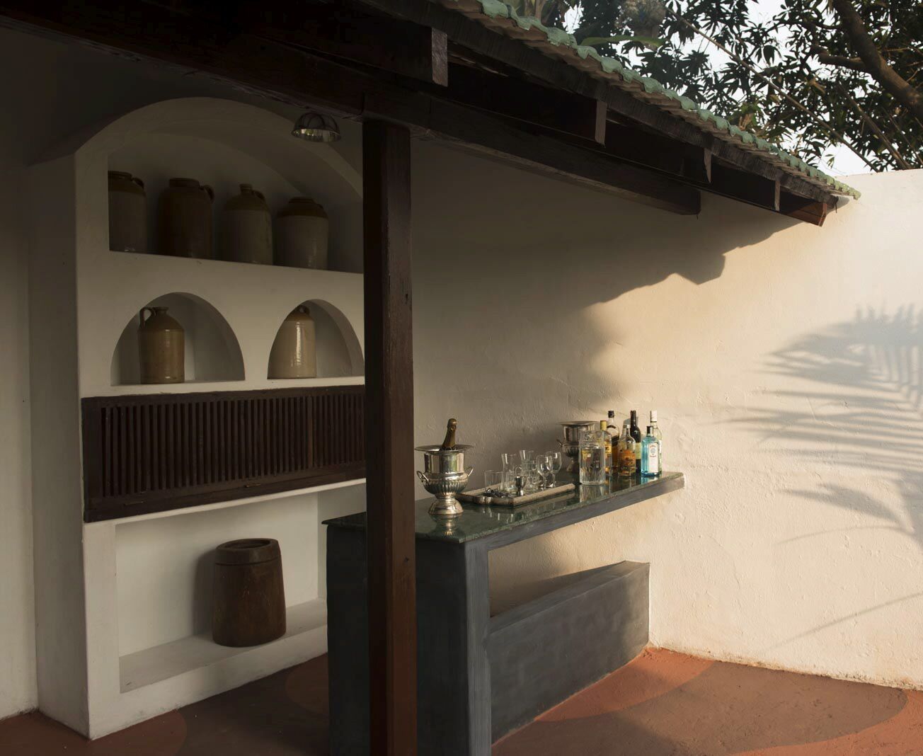 Een keukenhoek met een bar, planken met potten en een hangende lamp.