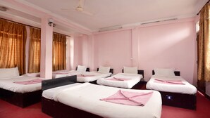 A hotel room with four single beds, a red carpet, and a ceiling fan. - Hotel Silver Home - Hostel (Kathmandu)
