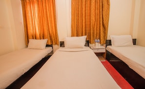 A hotel room with three single beds, a nightstand with water bottles, and a red carpet. - Hotel Silver Home - Hostel (Kathmandu)