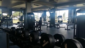 A gym with various weightlifting equipment, including dumbbells and benches. - Retaj Moroni Hotel (Moroni)