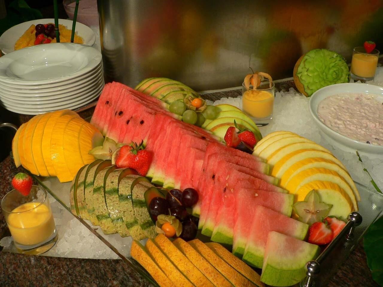 Un bufé con una variedad de frutas y un bol de comida.