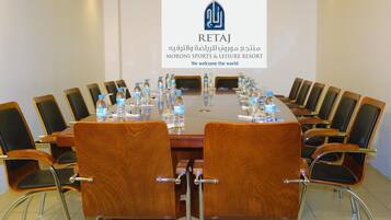 Une salle de conférence avec une longue table, des chaises et des bouteilles d’eau.
